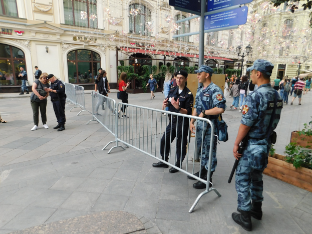 Polizeibeamte in Uniform stehen hinter Barrieren und blicken auf eine Menge, einige halten Waffen, mit Gebäuden, Bäumen und Laternen im Hintergrund während einer Anti-Terror-Operation in Wien, Österreich.