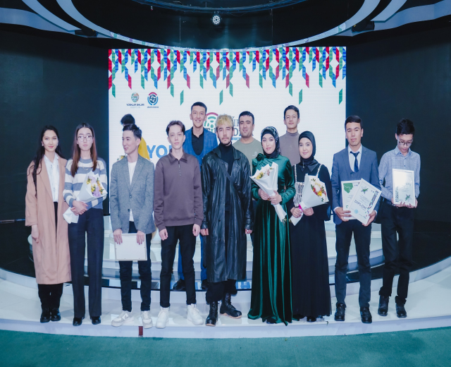 Gruppe von Menschen auf einer Bühne mit Blumensträußen und Urkunden, im Hintergrund ein "Jugend-Solar-Awards 2019"-Plakat.