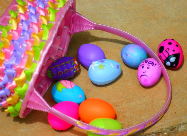 Ein geflochtener Korb mit mehreren bunten Ostereiern auf einer Wand.