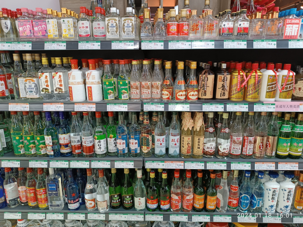 Vitrine mit verschiedenen Alkoholflaschen, jede mit Etiketten und Preisschildern, unter Deckenbeleuchtung ähnlich einem Spirituosenladen.
