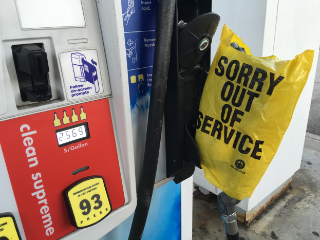 Tankstelle mit einem "Sorry Out of Service" Schild und einer gelben Abdeckung, die als Treibstoffspender gekennzeichnet ist.