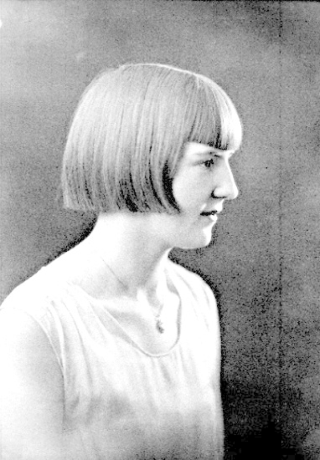 Ein Schwarz-Weiß-Foto einer Frau mit einem kurzen Bob-Haarschnitt, ihr Gesicht ist deutlich zu sehen, mit Blick zur Seite und leicht geöffneten Lippen.