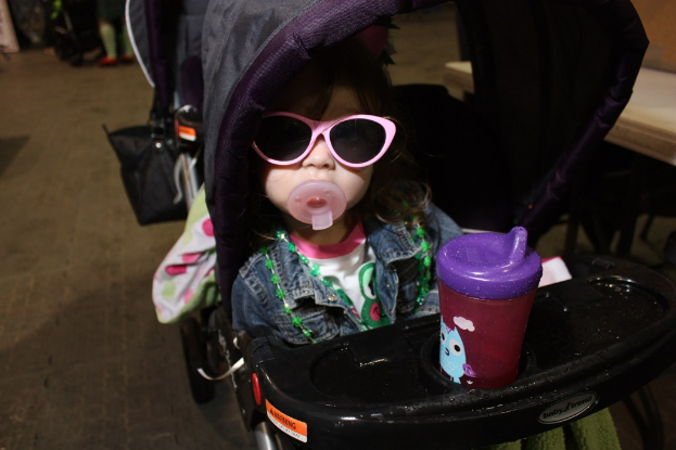 Kind sitzt in einem Laufgänger auf der Straße.