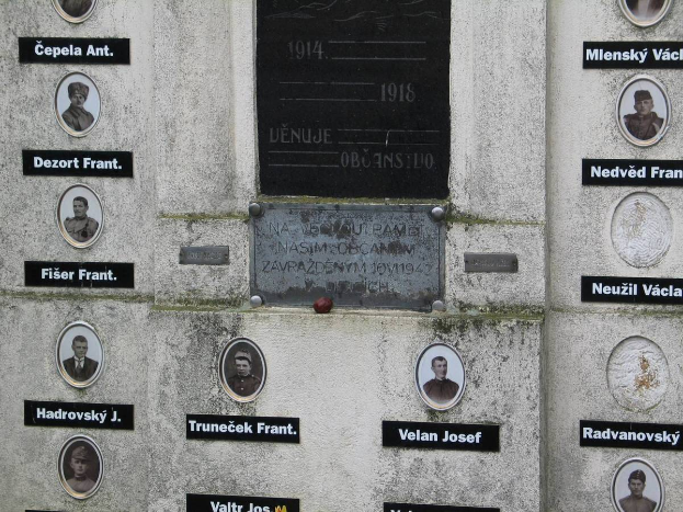 Ein Gedenkschild an einer Wand mit Bildern von Menschen und Text, das diejenigen ehrt, die im Zweiten Weltkrieg ihr Leben verloren haben.