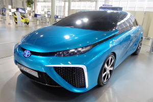 Ein blauer Toyota FT-1 Konzeptwagen, der auf der Internationalen Automobil-Ausstellung in Frankfurt gezeigt wird, umgeben von verschiedenen Objekten und anderen Autos.