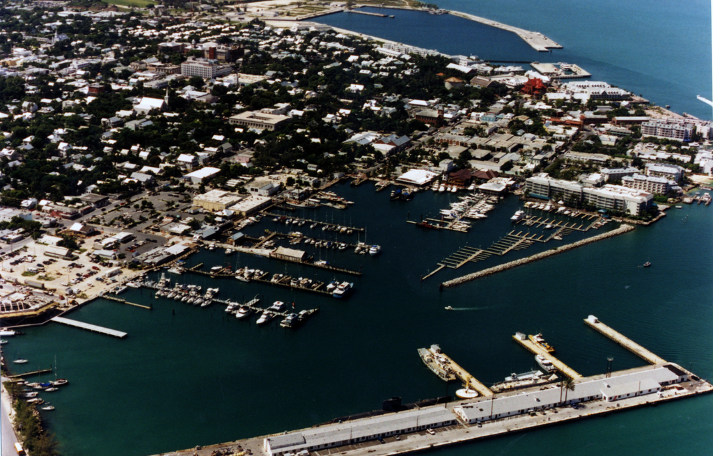 Eine Vogelperspektive einer Stadt mit zahlreichen Gebäuden, Meerwasser und einem Hafen an der Vorderseite, mit mehreren Schiffen.