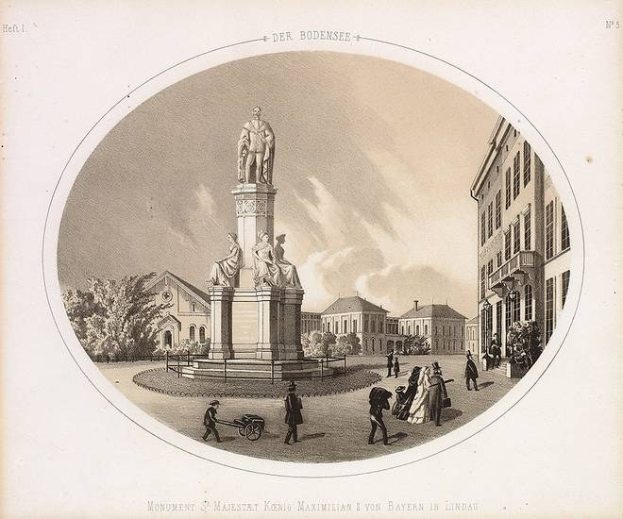 Schwarze und weiße Zeichnung der Statue des Heiligen Majestät König Maximilian I. von Bayern in einem Stadtplatz, umgeben von Gebäuden, Bäumen und Menschen, mit Text unten.