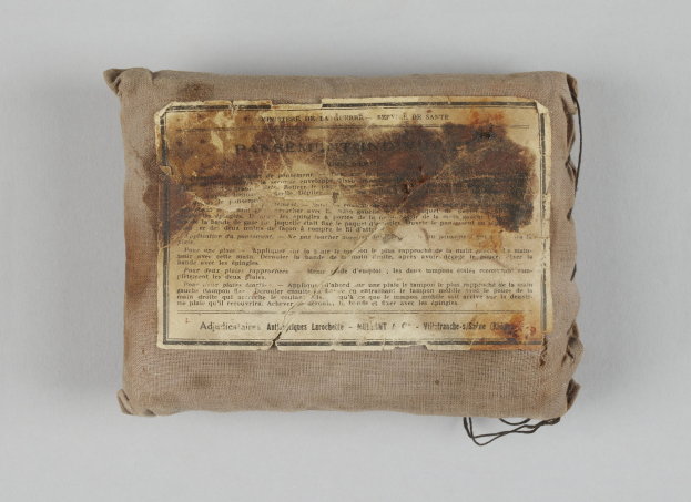 Kleiner Verbandskoffer mit einer Papierliste seiner Inhalte oder Anweisungen oben drauf.