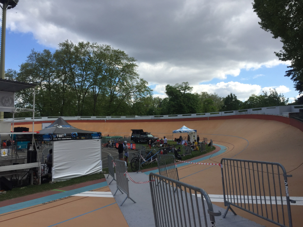 Gruppe von Radfahrern, die BMX-Räder auf einer Schmutzstrecke bei den UCI BMX-Weltmeisterschaften 2018 fahren, mit Zuschauern, Zelten und Fahrzeugen im Hintergrund.