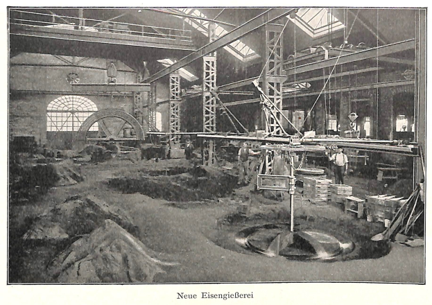 Schwarz-weiß-Foto einer frühen deutschen Fabrik mit Arbeitern, die Maschinen bedienen, umgeben von Metallstangen und -pfählen, beschriftet mit "Neue Eisenglebeerei, die erste Fabrik Deutschlands" unten.