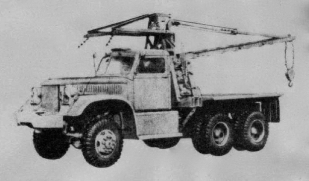 Ein Schwarz-Weiß-Foto eines großen, vierrädrigen Lkw mit einem Kran auf der Ladefläche und einem flachen Anhänger.