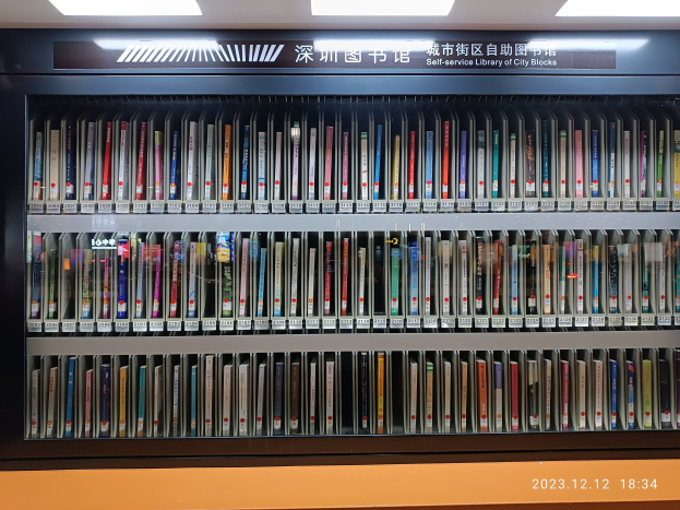 Eine gut beleuchtete Bibliothek mit Bücherregalen, einer Texttafel und einem Wasserzeichen, die an eine Selbstbedienungsbibliothek der Stadtblocks erinnert.