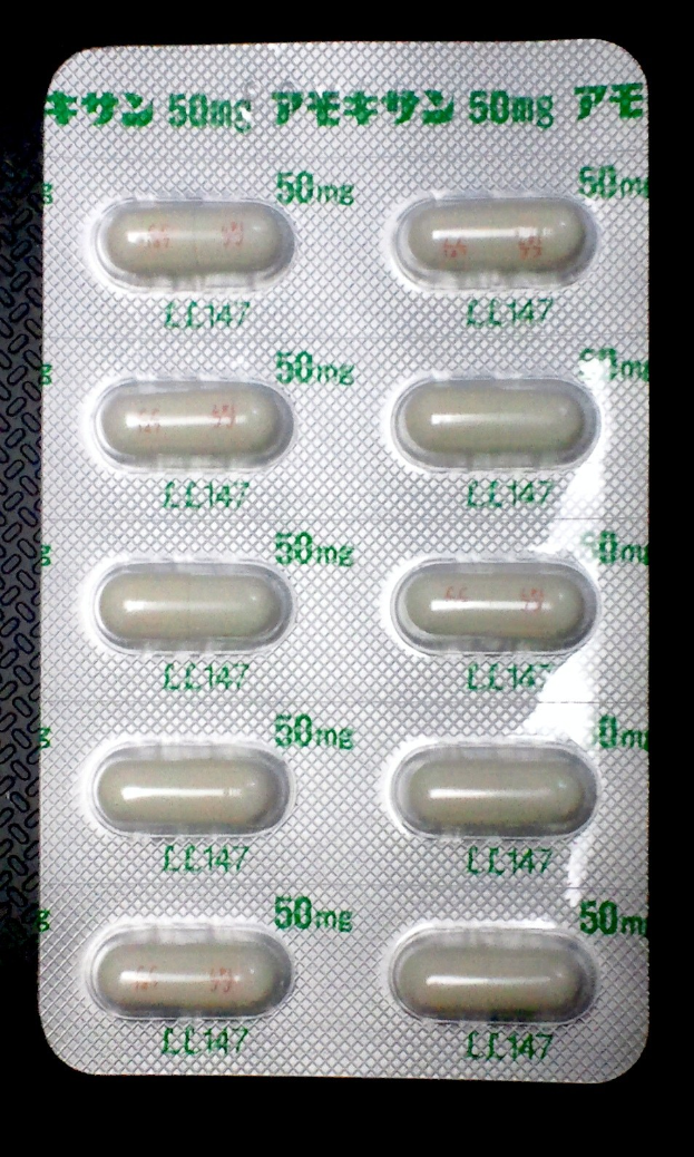 Weiße Pillen mit Aufdruck in einer Blisterverpackung auf schwarzem Hintergrund.