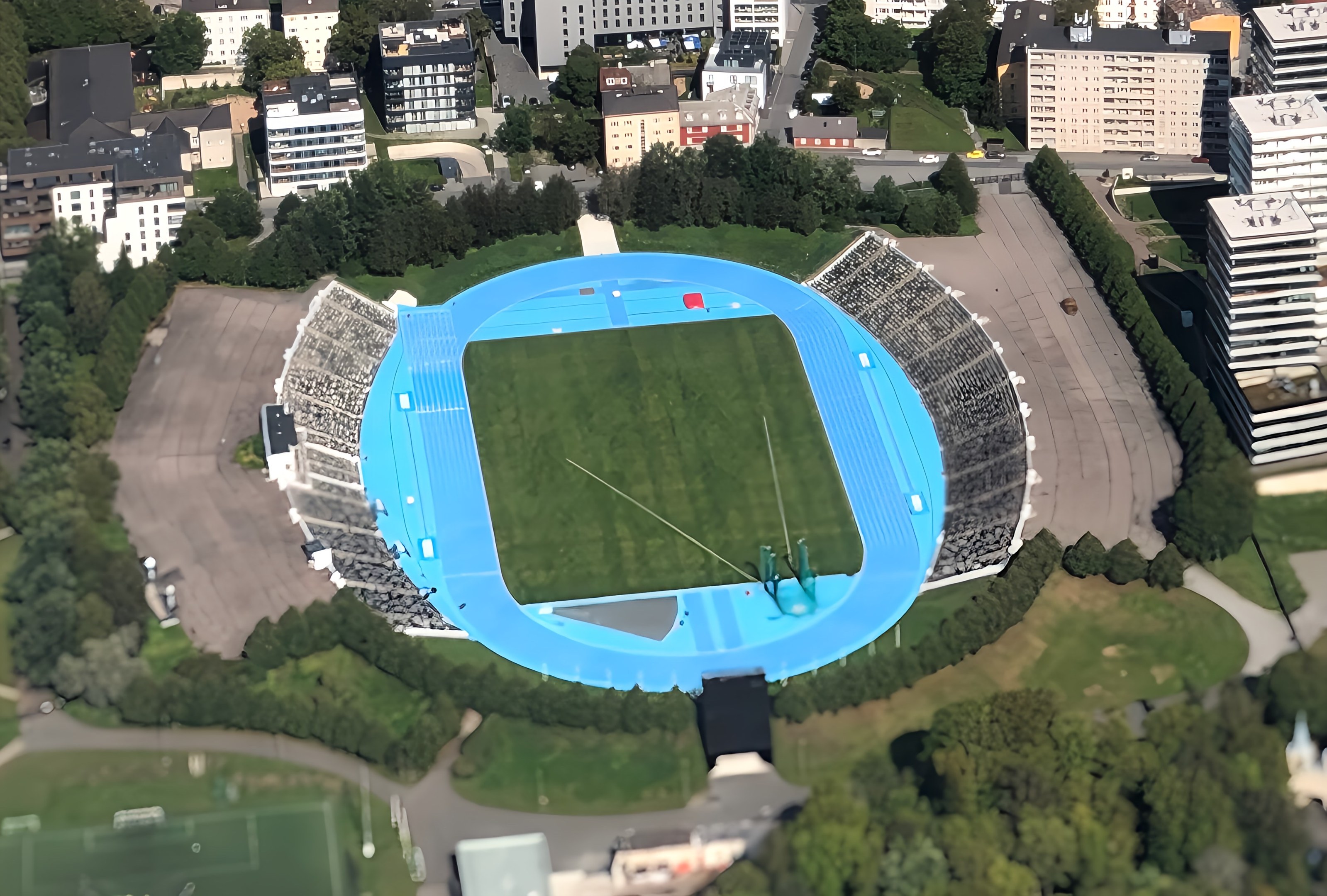Luftaufnahme des Olympiastadions in München, Deutschland, umgeben von städtischer Infrastruktur und Grünflächen.
