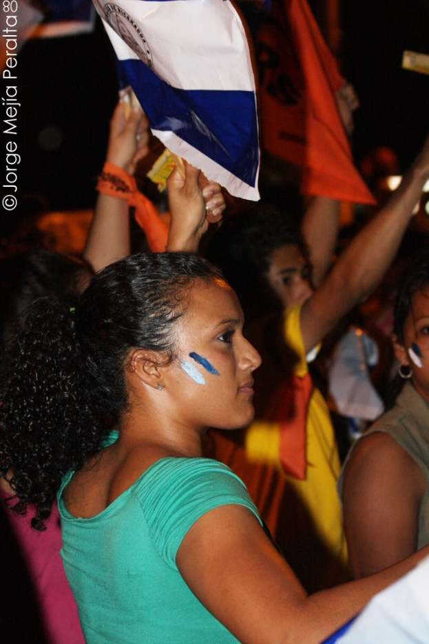 Frauen in grünen T-Shirts mit weißer Decke bei einer Demonstration, mit mehreren Mädchen dahinter.