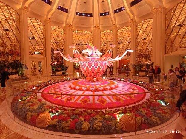 Außenansicht des Bellagio Hotels und Casinos in Las Vegas, Nevada, mit Menschen, dekorativen Blumenarrangements, Säulen und Beleuchtung.