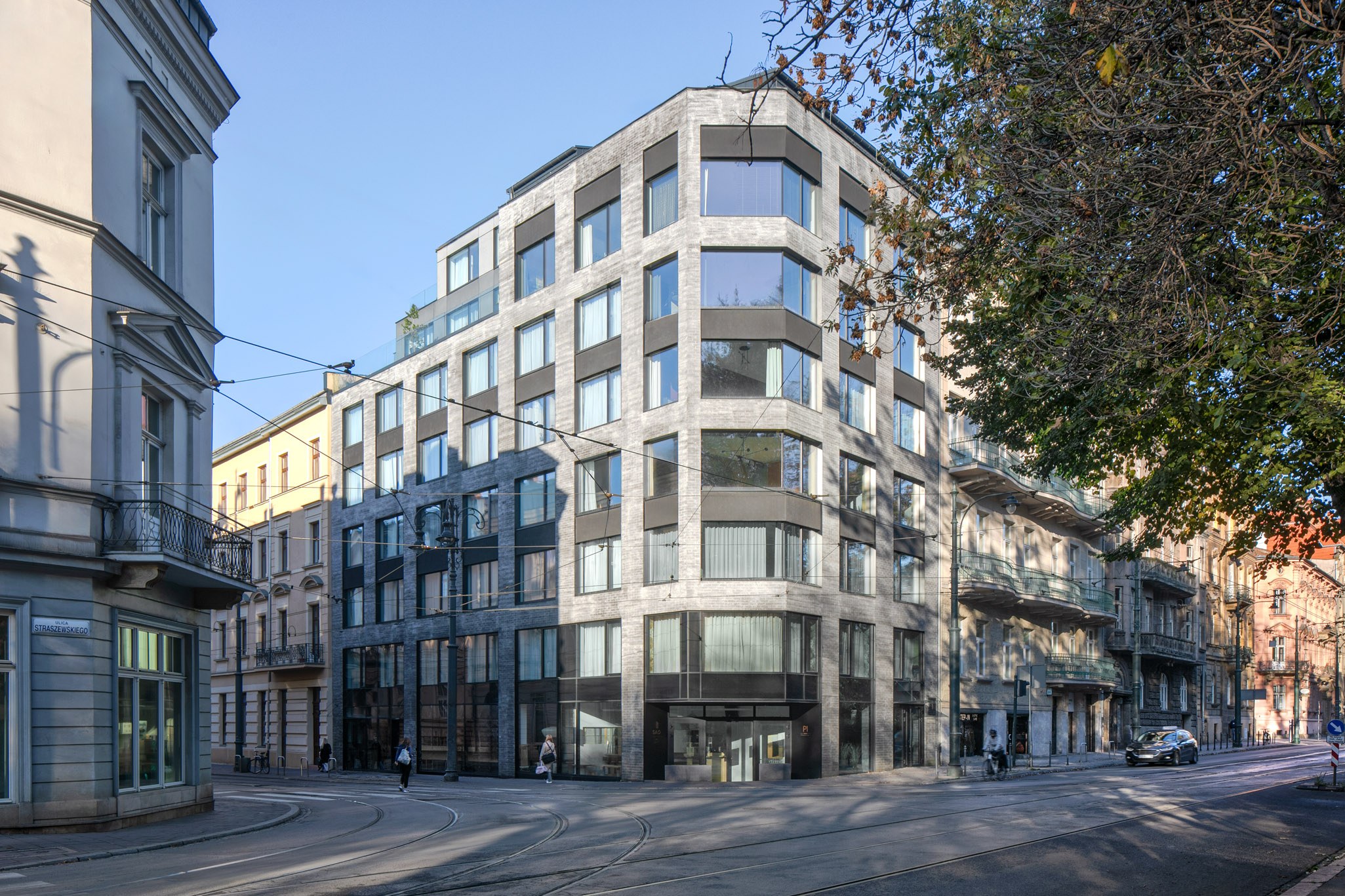 Großes Bürogebäude mit mehreren Fenstern, umgeben von Straßeninfrastruktur, Fahrzeugen, Fußgängern, Bäumen und einem bewölkten Himmel, als neue Firmenzentrale.