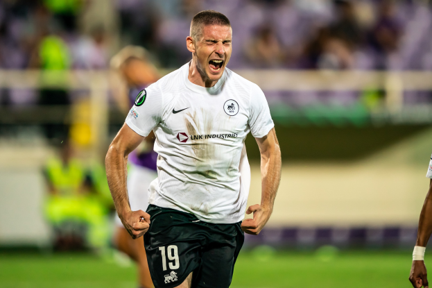 Ein Mann in weißem Hemd und schwarzen Shorts läuft auf einem Fußballfeld, umgeben von einer Gruppe von Menschen, die ein Tor während eines Spiels zwischen Leeds United und Melbourne Victory feiern.