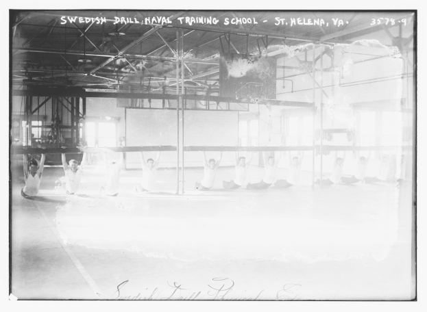 Black and white photo of a group performing gymnastics in a gym with poles, rods, windows, and a wall in the background, with text at the top and bottom.