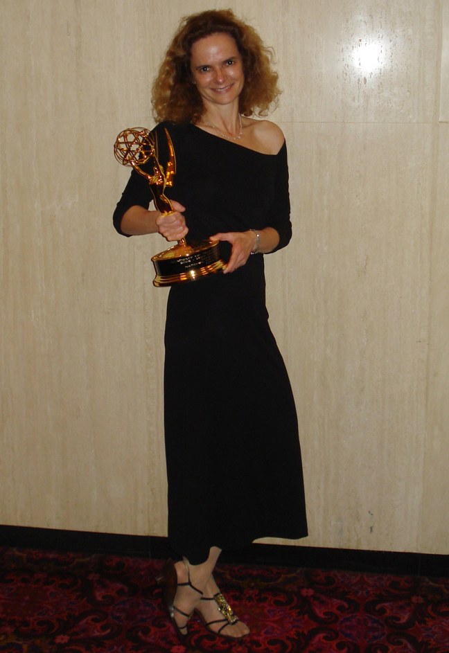 Frau in schwarzem Kleid mit Emmy-Award auf dem roten Teppich