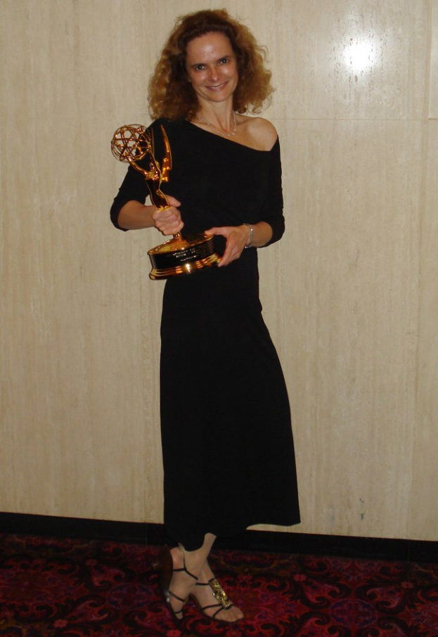 Frau in schwarzem Kleid mit Emmy-Award auf dem roten Teppich