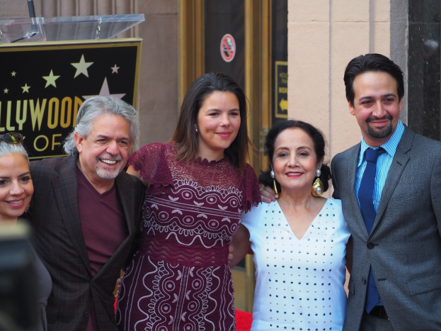 Gruppe von Menschen auf einem roten Teppich bei der Zeremonie auf dem Hollywood Walk of Fame mit einer Tafel, einem Glaspodest und einer Wand im Hintergrund.