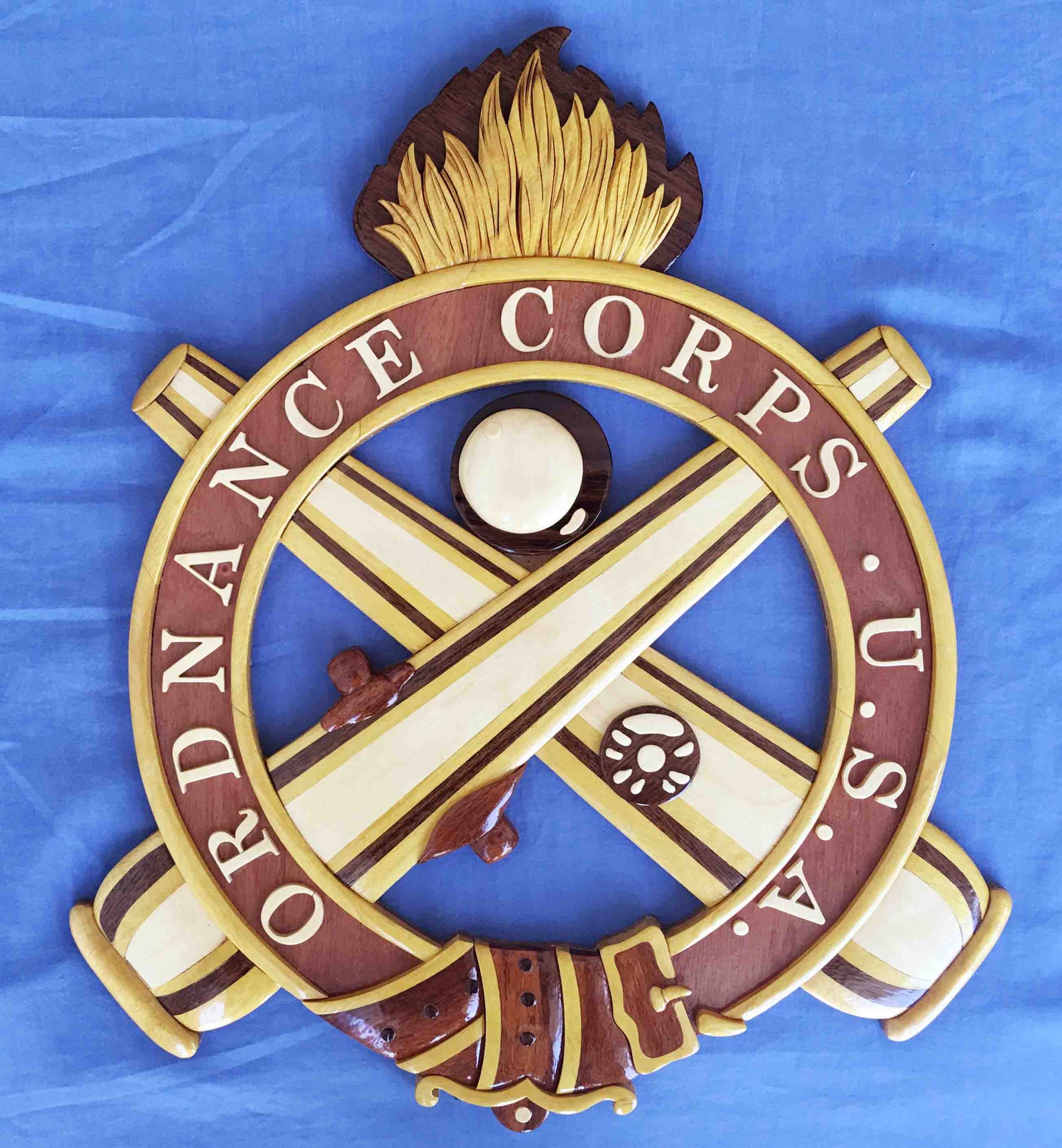 Holzschild mit "Ordnance Corps" in schwarzer Schrift, mit einem weißen Stern auf einem navy-Blue-Hintergrund mit goldener Umrandung, auf blauem Tuch montiert.
